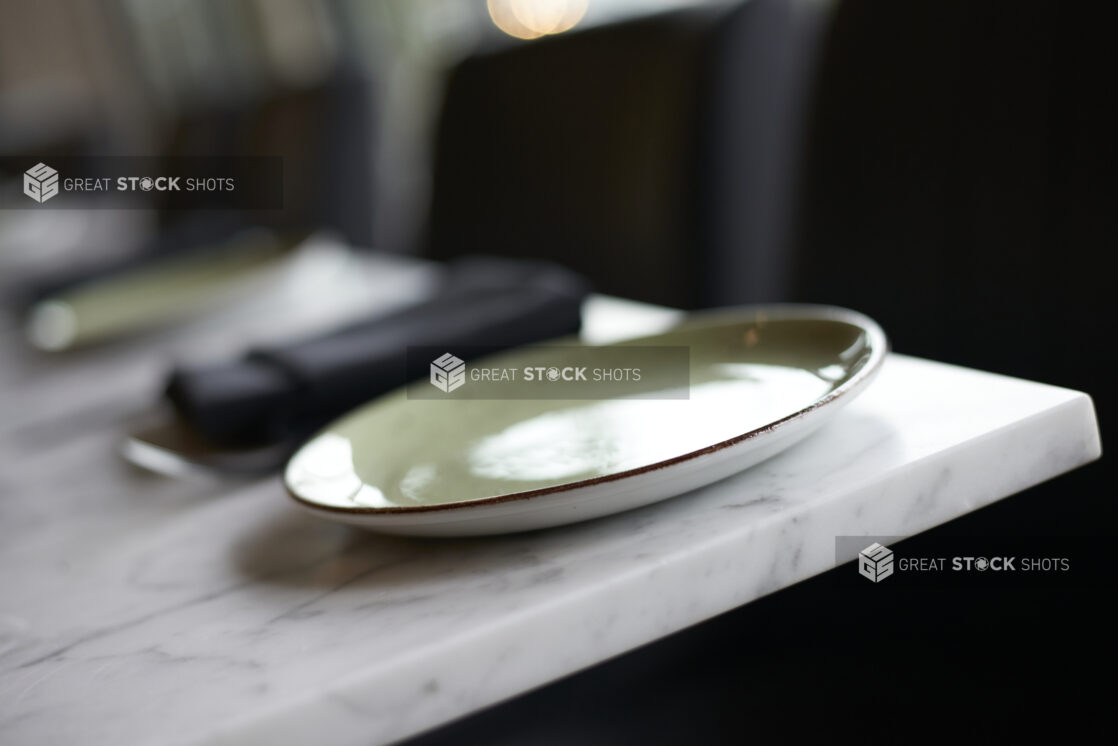 Green and white ceramic plate on a white marble tabletop, close-up