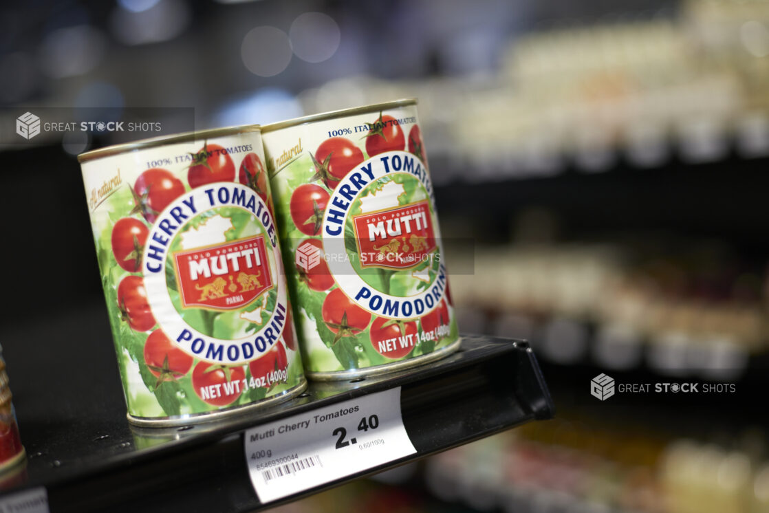 Two cans of cherry tomatoes on a shelf