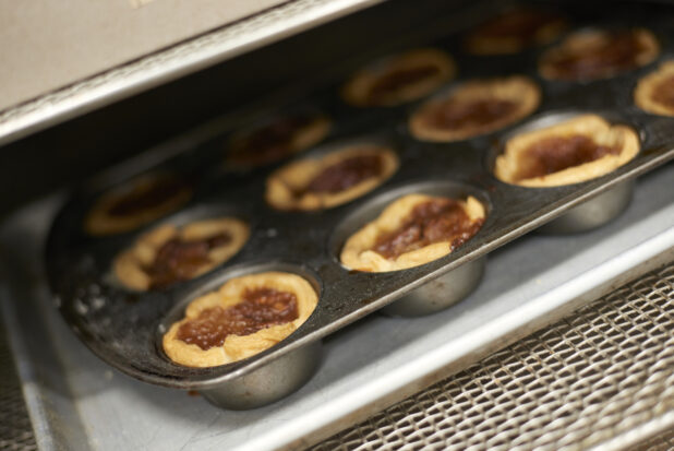 Freshly Baked Butter Pecan Tarts in a Muffin Baking Tin Coming Out of an Oven in a Gourmet Grocery Store Kitchen Setting