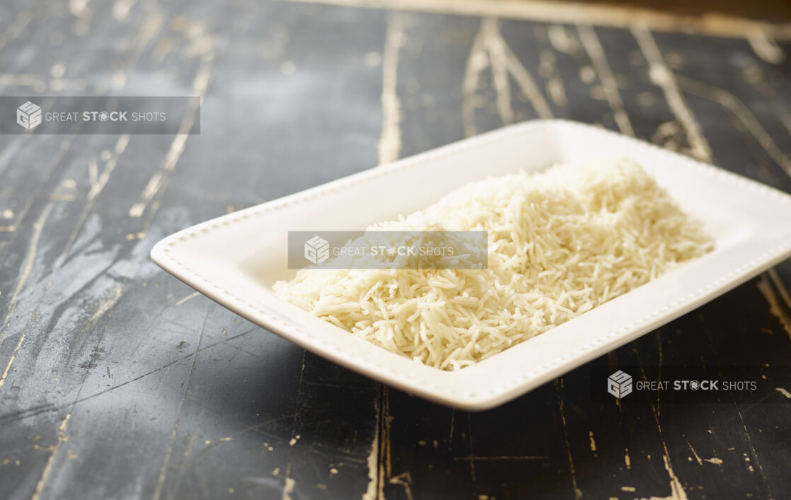 A White Ceramic Platter of White Rice, a Side Dish for Catering, on a Black Painted Weathered Wood Table