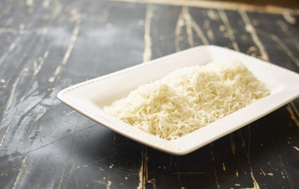 A White Ceramic Platter of White Rice, a Side Dish for Catering, on a Black Painted Weathered Wood Table