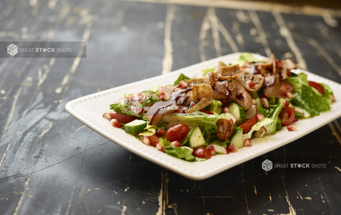 Garden Salad with Gyro Meat and Balsamic Vinaigrette Drizzle on a White Ceramic Platter on a Black Painted Wooden Table