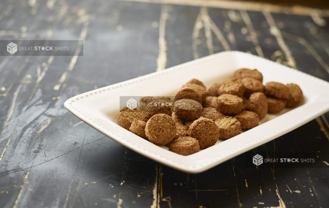 A White Ceramic Platter of Middle Eastern Falafel Balls for Catering on a Black Painted Weathered Wood Table