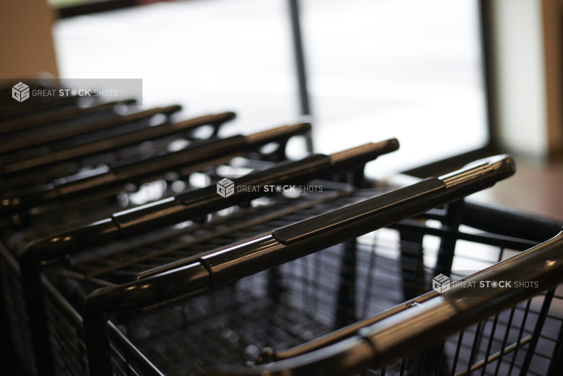 Line of nested steel shopping carts, close-up, bokeh effect