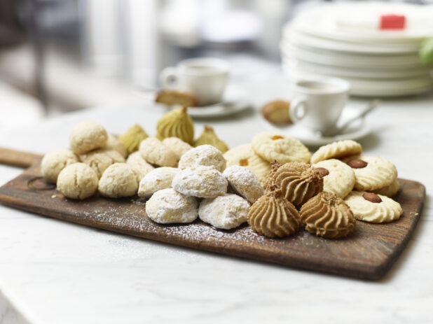 Assorted Italian Butter Cookies on a Wooden Platter Board with Espresso Coffee in Ceramic Cups on a Marble Surface