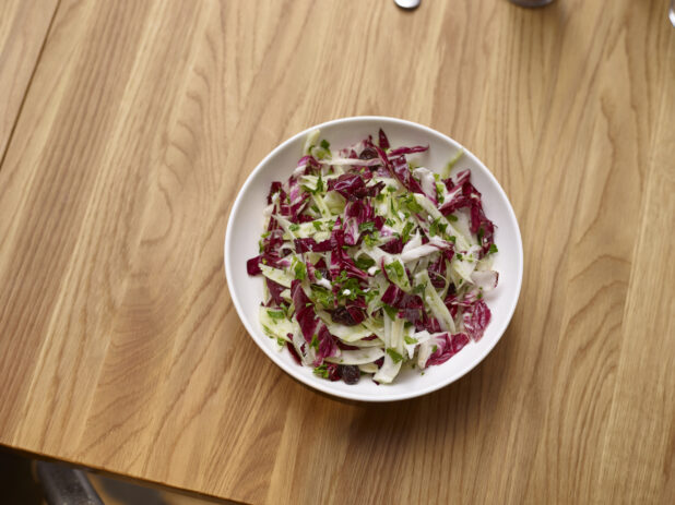Overhead View of an Italian Radicchio and Fennel Salad in a Round White Ceramic Salad Bowl on a Wooden Table
