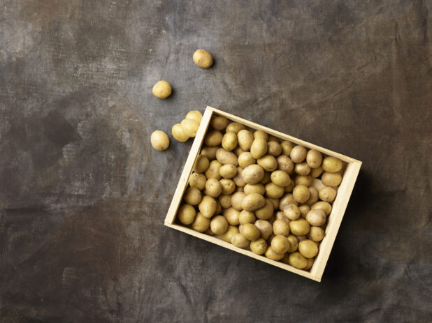 Wooden crate of white new potatoes