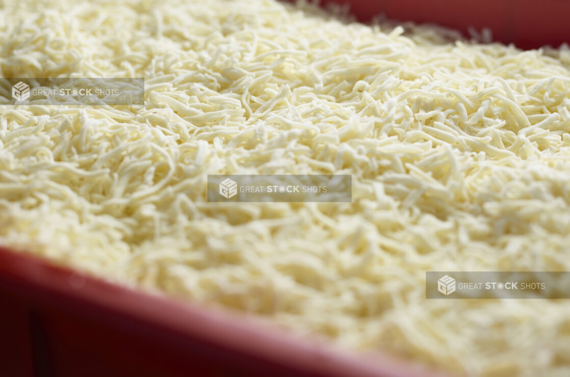 Close up of shredded mozzarella cheese in a red container