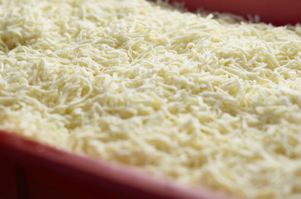 Close up of shredded mozzarella cheese in a red container