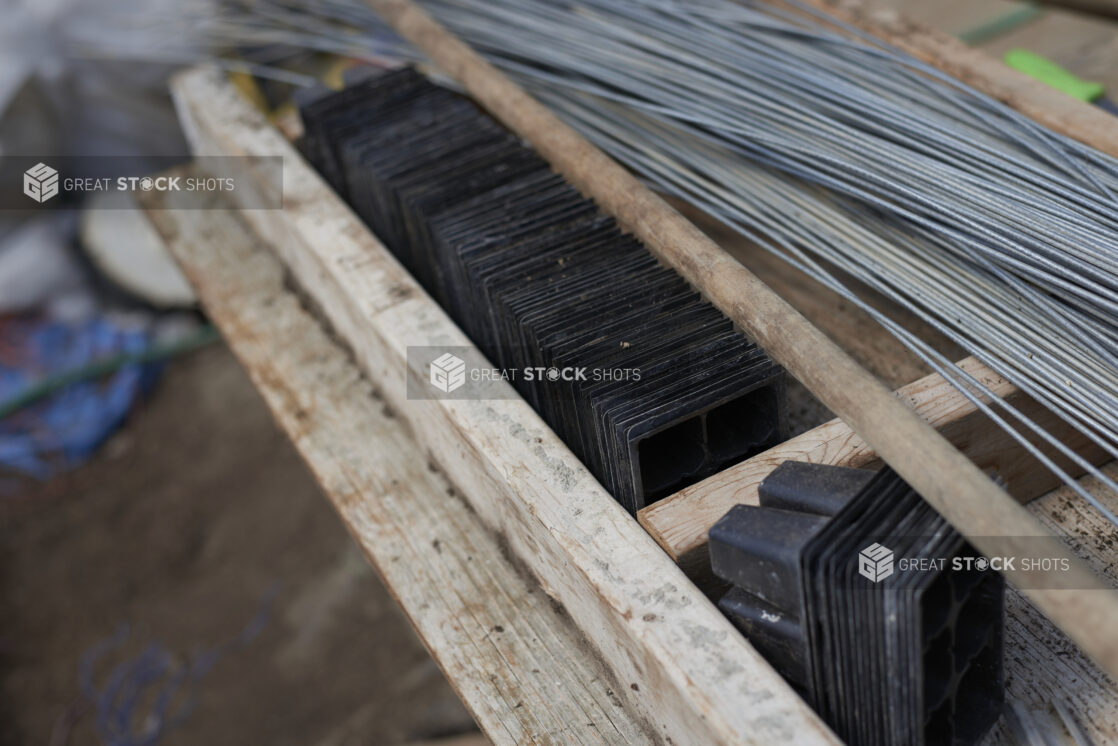 Close Up of a Wooden Potting Table with Black Plastic Seedling Trays and Stainless Steel Wires in a Greenhouse Setting