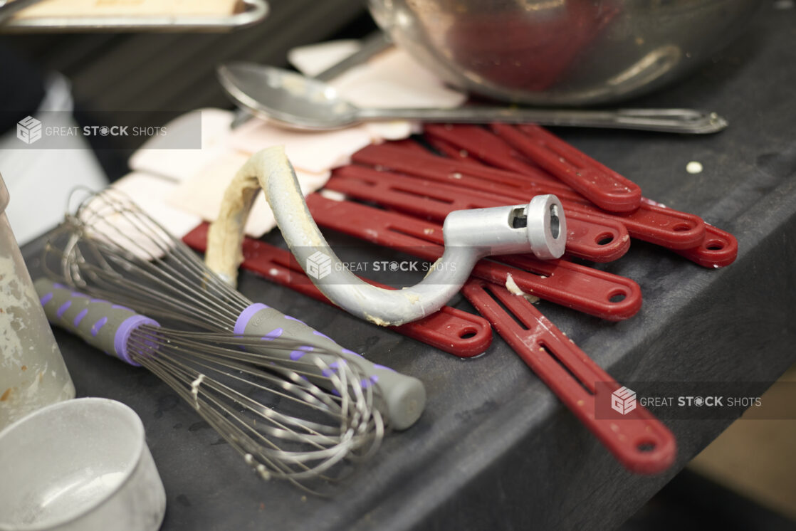 Used baking utensils on a black countertop