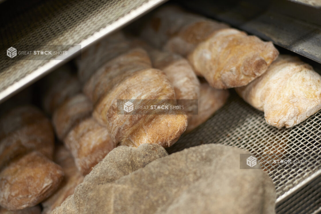 Crusty bread rolls piled on a wire rack, close-up