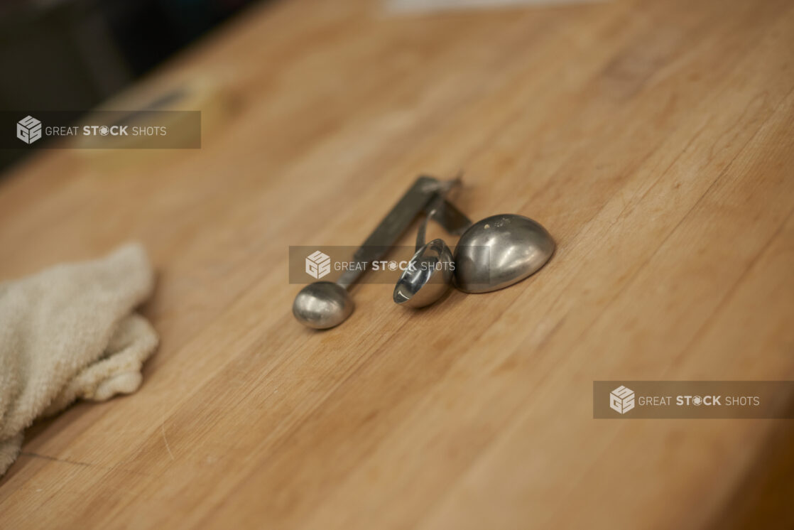 Close Up of Metal Measuring Spoons on a Wooden Counter in the Bakery Kitchen of a Gourmet Grocery Store