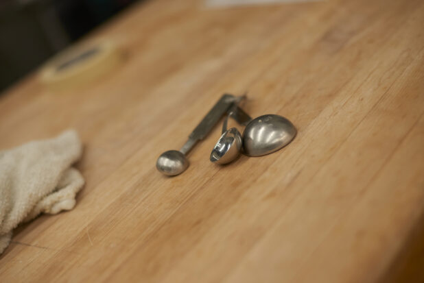 Close Up of Metal Measuring Spoons on a Wooden Counter in the Bakery Kitchen of a Gourmet Grocery Store