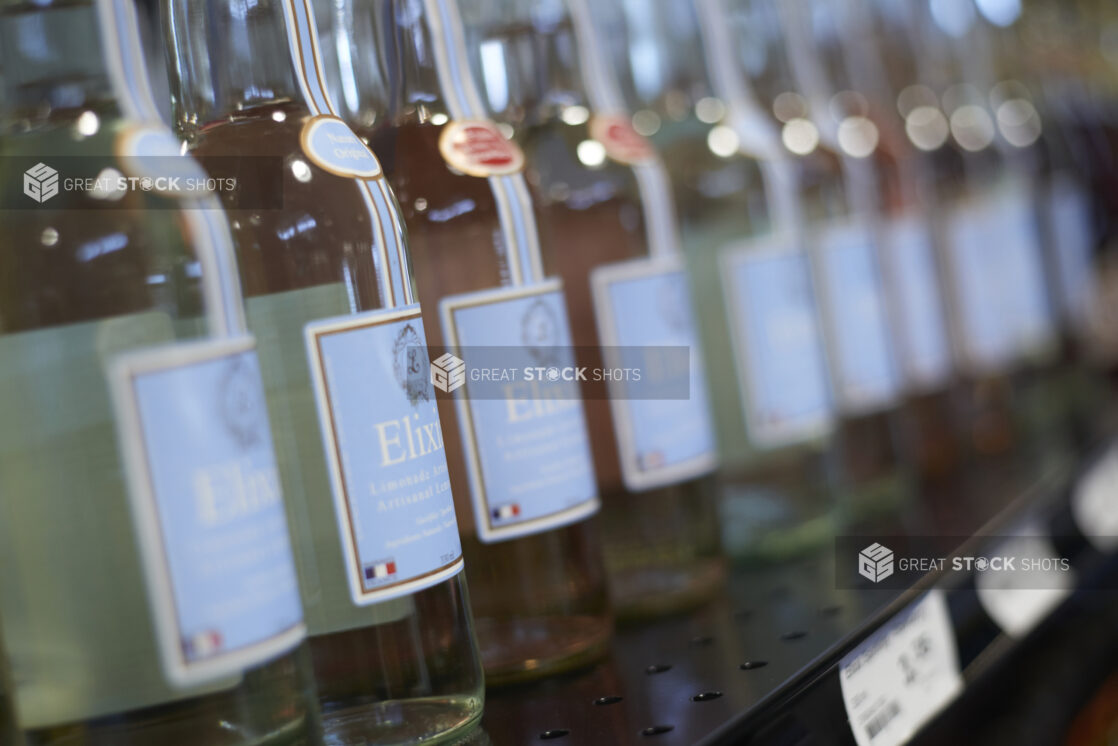 A Row of Gourmet Bottled Beverages - Elixia Sparkling French Lemonade - on a Shelf in a Gourmet Grocery Store Setting