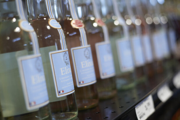 A Row of Gourmet Bottled Beverages - Elixia Sparkling French Lemonade - on a Shelf in a Gourmet Grocery Store Setting