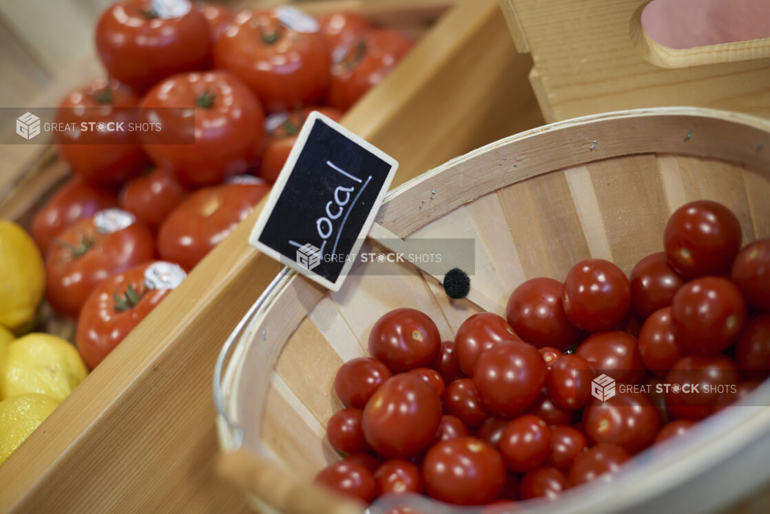 Cherry tomatoes in a mini bushel basket with beefsteak tomatoes and lemons in the background