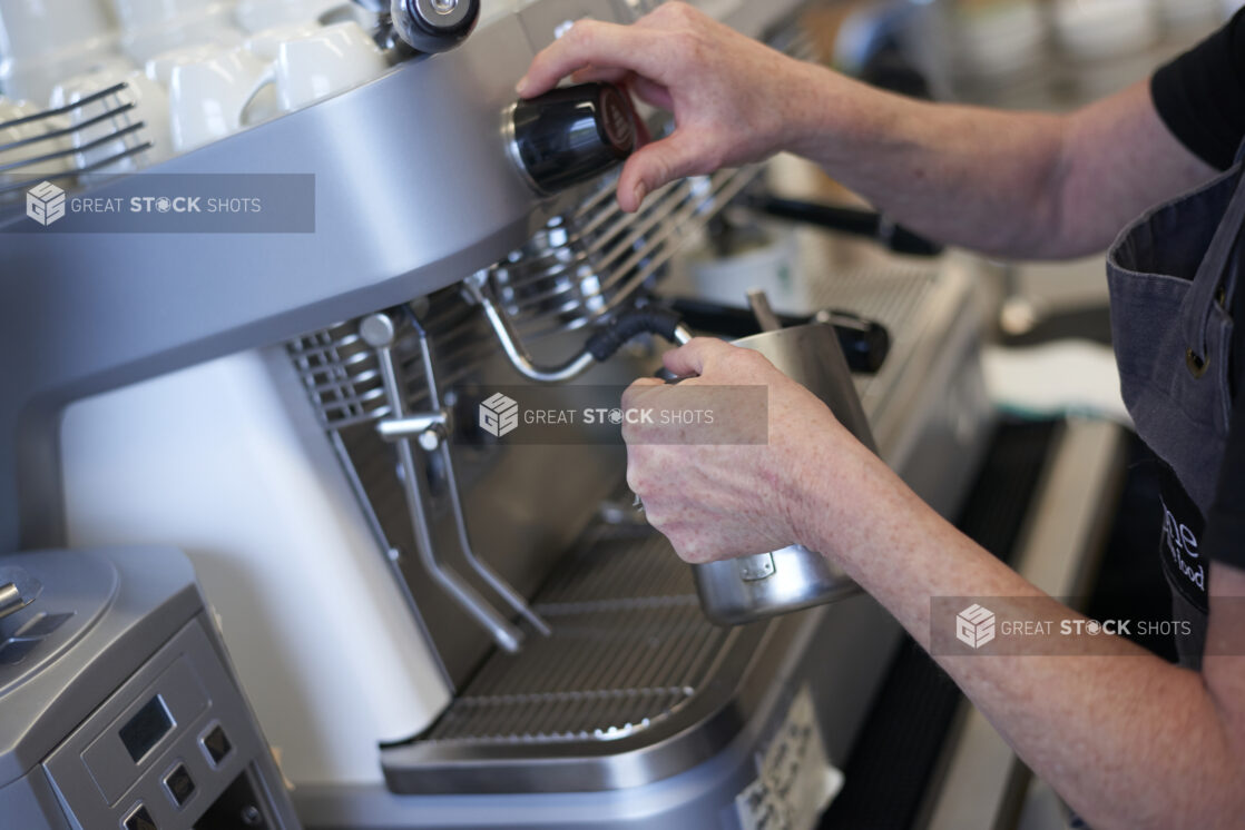 Close Up of a Barista's Hands Preparing a Latte on an Commercial Espresso Coffee Machine in a Cafe Located in a Gourmet Grocery Store