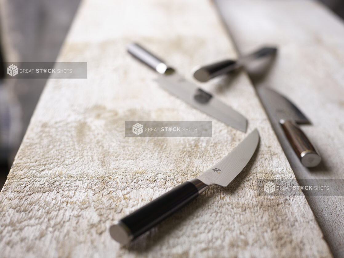 Kitchen knives on a white weathered wood surface, close-up