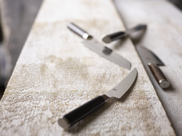 Kitchen knives on a white weathered wood surface, close-up