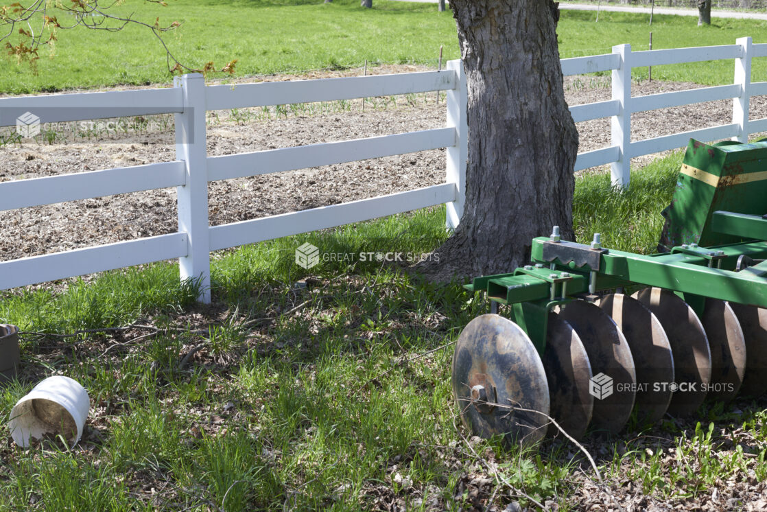 Close Up of a Green Disc Harrow Cultivating Farming Equipment in a Pasture with a White Fence on a Farm in Ontario, Canada