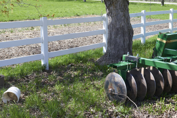 Close Up of a Green Disc Harrow Cultivating Farming Equipment in a Pasture with a White Fence on a Farm in Ontario, Canada