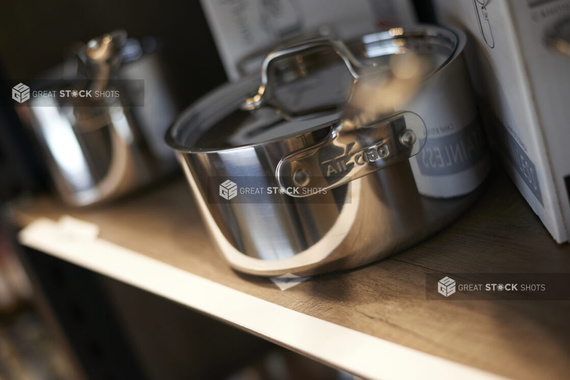 Stainless steel saucepan on a shelf, handle foreshortened and out of focus