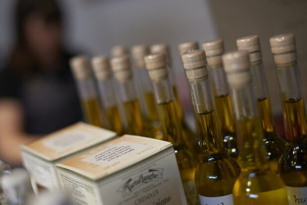 Close Up of Boxes of Tartuflanghe Italian Truffles and Bottles of High Quality Extra Virgin Olive Oil on a Shelf in a Gourmet Grocery Store Setting