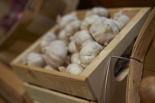 Close Up of a Wooden Crate of Garlic Bulbs in the Produce Section of a Gourmet Grocery Store
