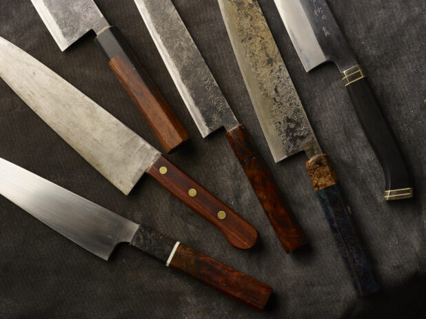 A collection of Japanese kitchen knives on a dark cloth background