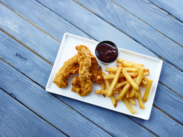 Overhead View of a Kid's Chicken Finger Combo Meal with Fries and a Side of BBQ Dipping Sauce on a White Rectangular Platter on a Painted Wood Surface