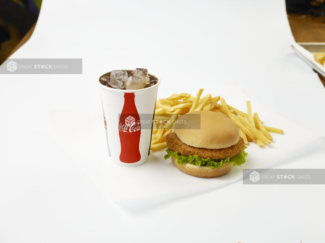 Fried Chicken Sandwich Combo with French Fries and a Fountain Soda in a Paper Cup with Ice Cubes, on a White Background for Isolation