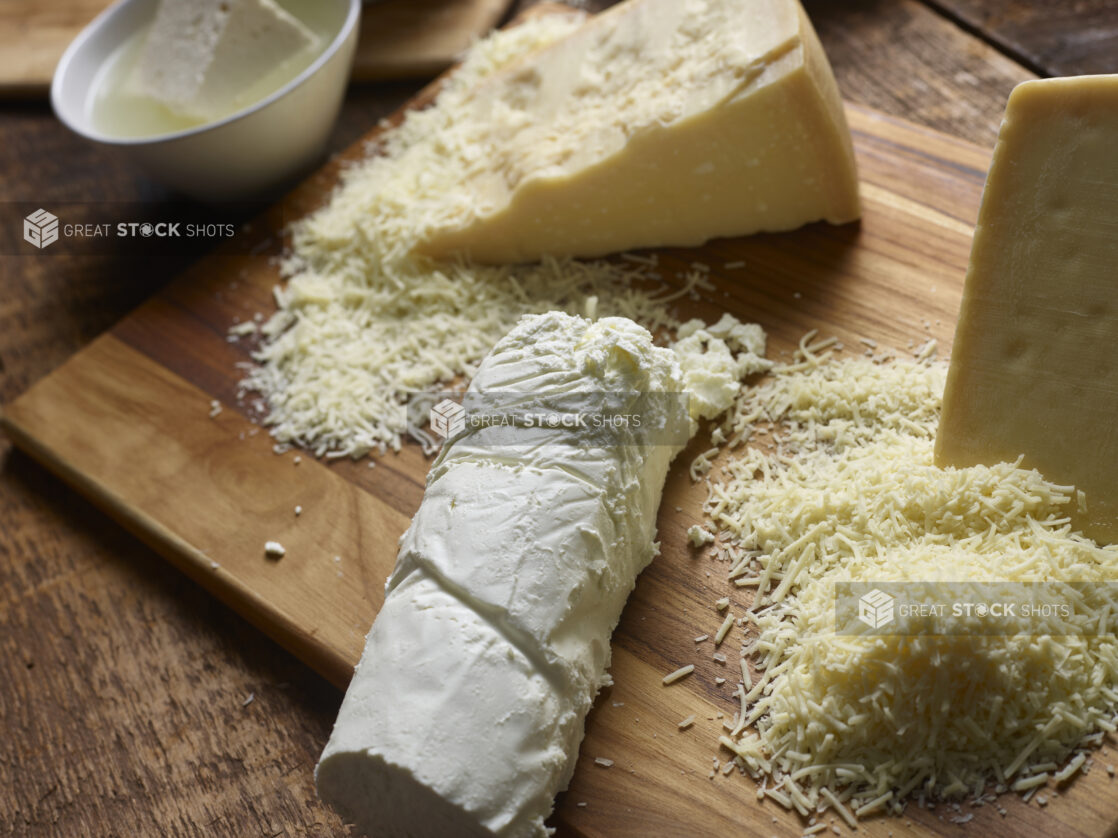 Various cheeses on a wooden cutting board - goat cheese, parmesan, and feta cheese