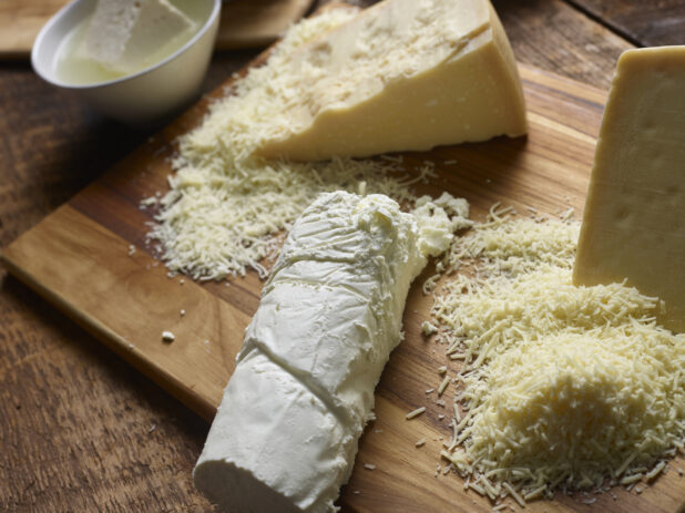 Various cheeses on a wooden cutting board - goat cheese, parmesan, and feta cheese