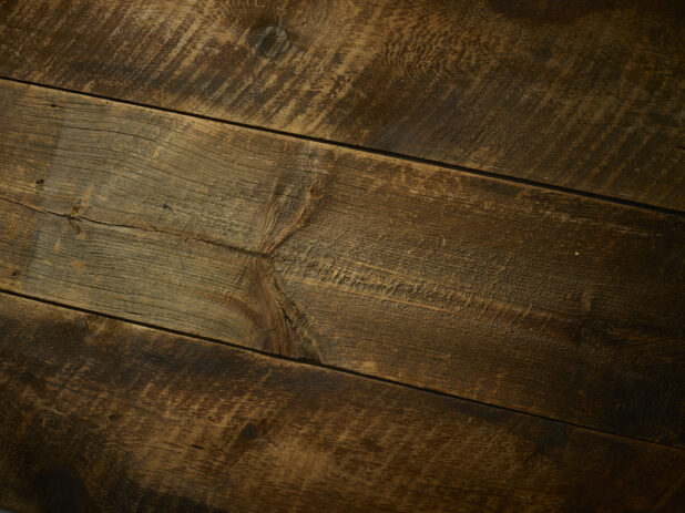 Full background of aged dark wood planks with rustic saw marks, tilted