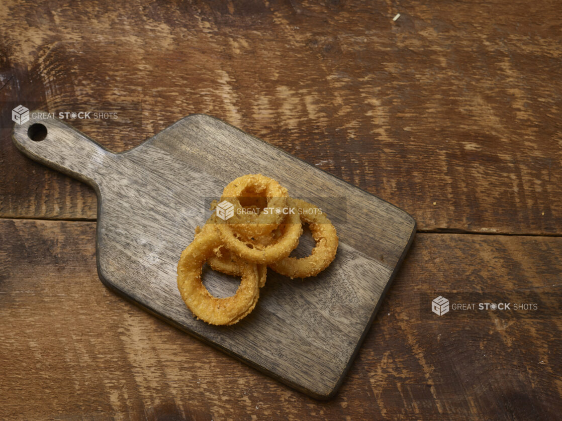 Fried onion rings on a wooden board on a rustic wooden background