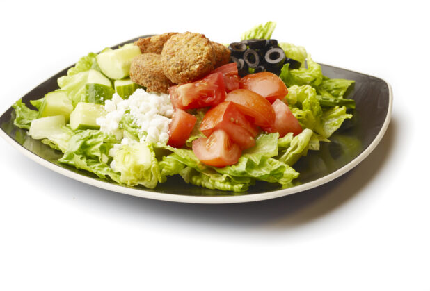 Plain Greek Salad with Chopped Tomatoes, Cucumber, Black Olives, Feta and Falafel Balls on a Square Black Ceramic Dish, on a White Background for Isolation