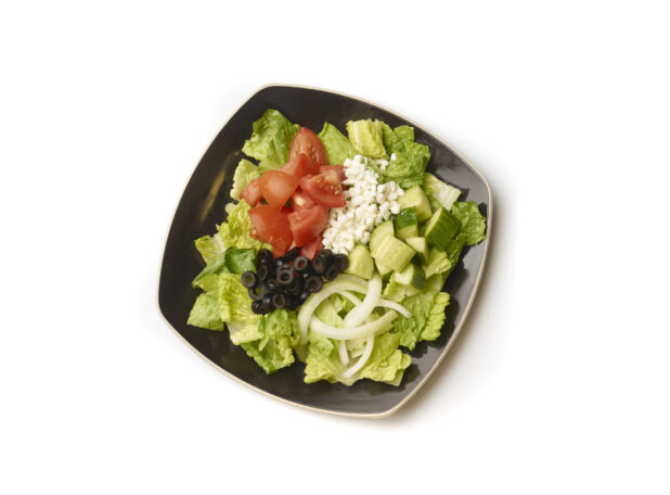 Overhead View of a Plain Greek Salad with Chopped Tomatoes, Cucumber, Black Olives, Feta and White Onions on a Square Black Ceramic Dish, on a White Background for Isolation