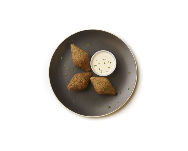 Overhead View of Diamond Shaped Falafel Balls on a Black Ceramic Dish with a Side of Creamy Tahini Dipping Sauce, Shot on a White Background for Isolation