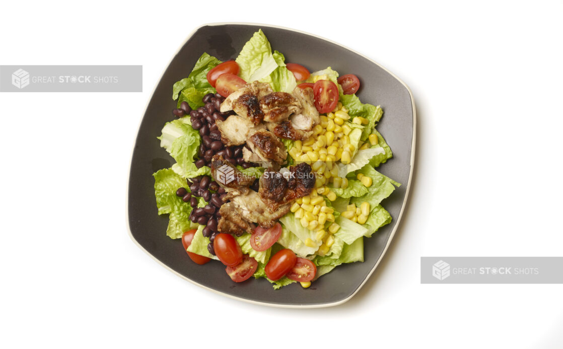 Overhead View of a Chicken Shawarma Salad with Corn and Black Beans on a Square Black Ceramic Dish, on a White Background for Isolation