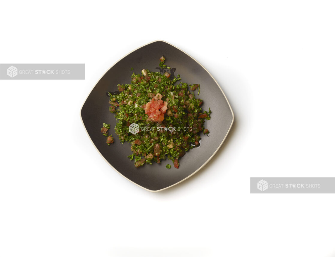 Overhead View of a Square Black Ceramic Dish of Tabbouleh – a Levantine Salad – with Fresh Diced Tomatoes for Garnish, on a White Background for Isolation