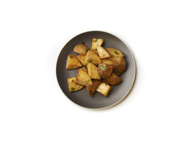 Overhead View of Garlic Potatoes on a Round Black Ceramic Dish, on a White Background for Isolation