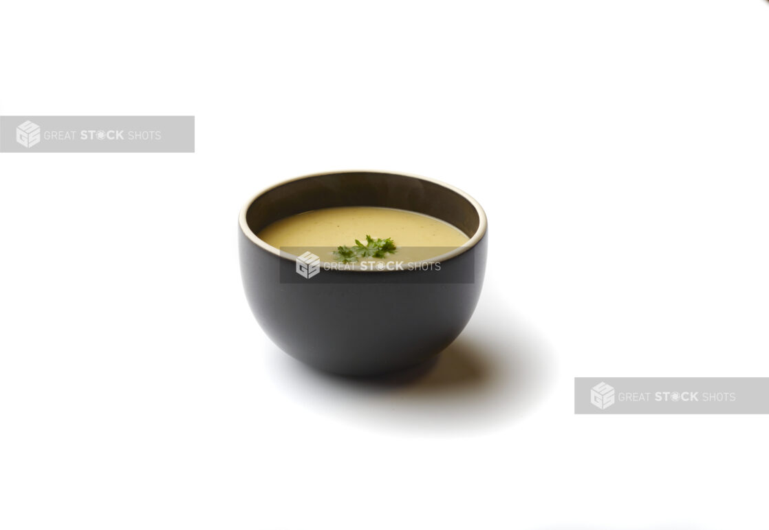 Bowl of Lentil and Swiss Chard Vegan Soup with a Fresh Parsley Garnish, on a White Background for Isolation