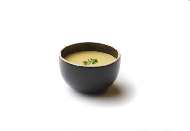 Bowl of Lentil and Swiss Chard Vegan Soup with a Fresh Parsley Garnish, on a White Background for Isolation