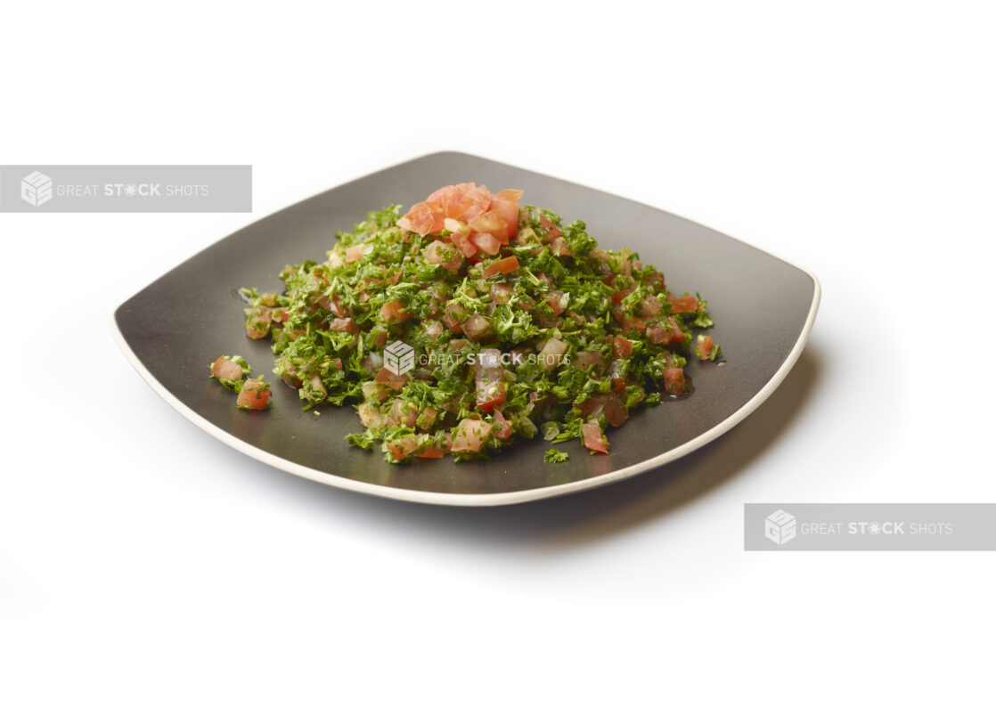 Tabbouleh – a Levantine Salad – with Fresh Diced Tomatoes for Garnish, on a Square Black Ceramic Dish on a White Background for Isolation