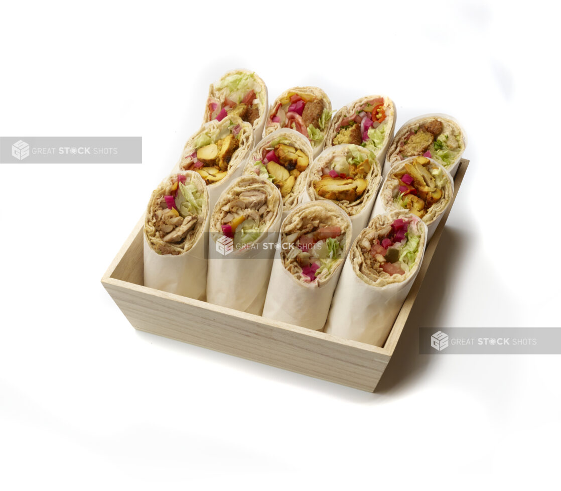 Deep Square Wood Serving Tray Filled with Chicken Shawarma, BBQ Chicken and Falafel Pita Wraps with Fresh Vegetable Toppings, Rolled in Parchment Paper on a White Background for Isolation