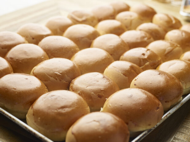 Close Up of a Baking Pan Full of Freshly Baked Hamburger Buns on a Wooden Table