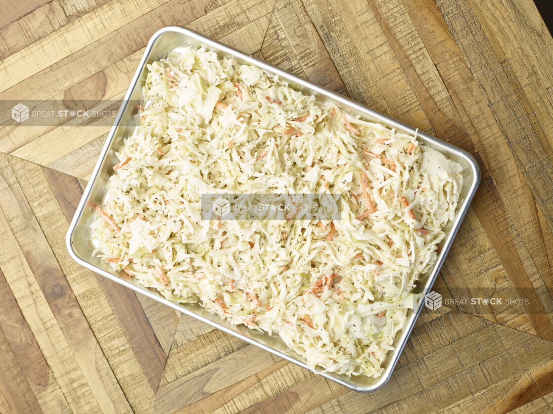 Overhead View of a Metal Baking Sheet Full of Prepared Creamy Coleslaw for Catering or a Party Tray, on a Wooden Parquet Table