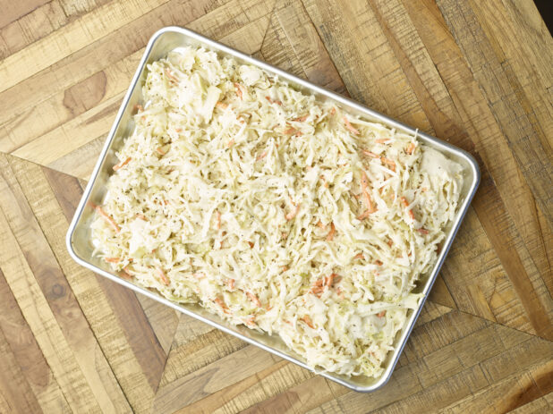 Overhead View of a Metal Baking Sheet Full of Prepared Creamy Coleslaw for Catering or a Party Tray, on a Wooden Parquet Table