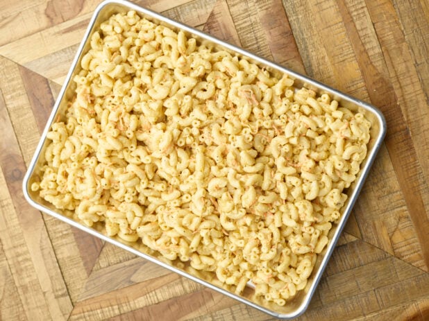 Overhead View of a Metal Baking Sheet Full of Prepared Macaroni Pasta Salad for Catering or a Party Tray, on a Wooden Parquet Table